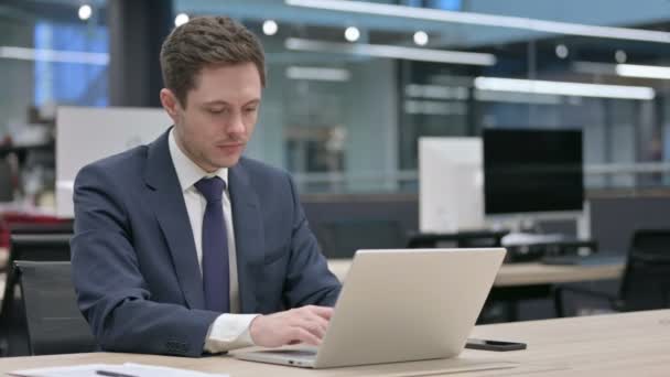 Επιχειρηματίας κοιτάζοντας κάμερα, ενώ χρησιμοποιώντας το Laptop στο γραφείο — Αρχείο Βίντεο