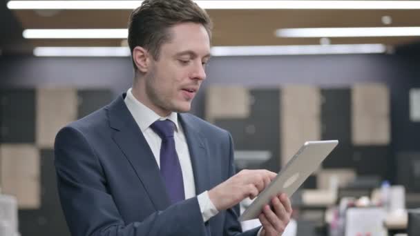 Бизнесмен празднует успех на планшете в офисе — стоковое видео