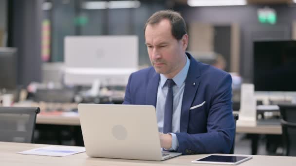 Geschäftsmann denkt während der Arbeit am Laptop im Büro — Stockvideo