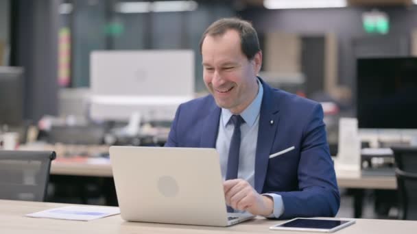 ビジネスマンがオフィスのノートパソコンでビデオ通話で話す — ストック動画