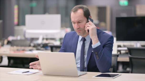 Boze zakenman in gesprek over de telefoon op kantoor — Stockvideo