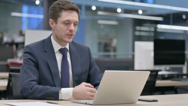 Бизнесмен разговаривает на видео звонок на ноутбуке в офисе — стоковое видео