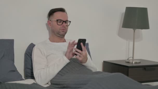 Lässige Handhabung des Smartphones im Bett — Stockvideo