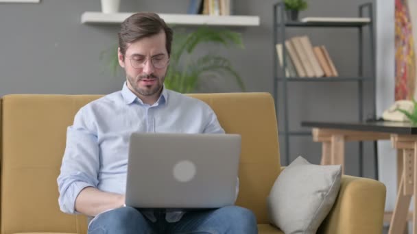 Jovem com laptop tosse no sofá — Vídeo de Stock