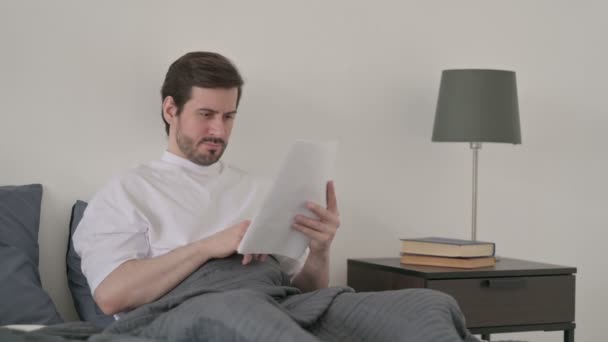 ベッドで文書を読む若い男 — ストック動画