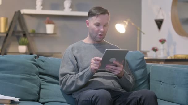 ソファの上のタブレット上のカジュアル男祝いの成功 — ストック動画