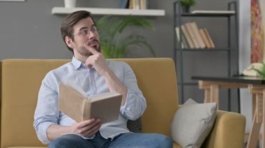 Genç Adam Koltukta Kitap okurken Düşünüyor 