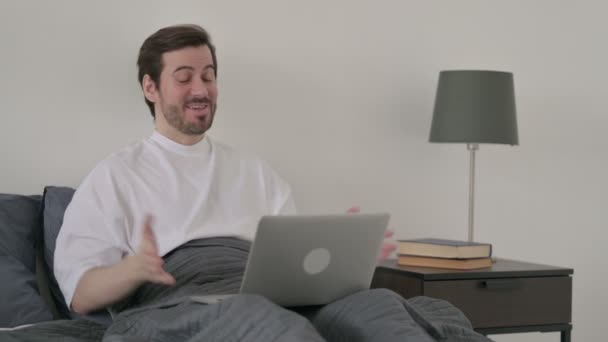 Νεαρός κάνει βιντεοκλήση στο φορητό υπολογιστή στο κρεβάτι — Αρχείο Βίντεο