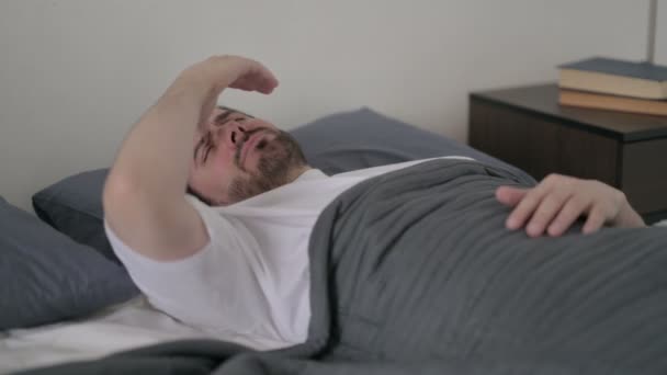 Νεαρός που έχει πονοκέφαλο ενώ κοιμάται στο κρεβάτι — Αρχείο Βίντεο