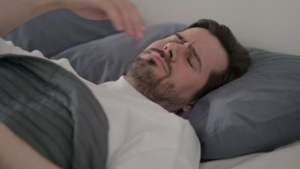 Молодий чоловік болить під час сну в ліжку — стокове відео