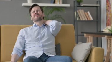 Genç adam koltukta otururken boynu ağrıyor. 