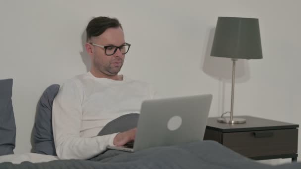 ベッドでノートパソコンで働く中年男性 — ストック動画