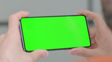 Close Up of Creative Young Man Watching Smartphone with Chroma Screen 