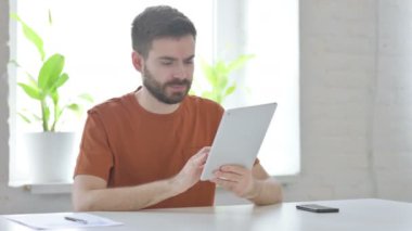 Creative Young Man having Loss on Tablet in Office 