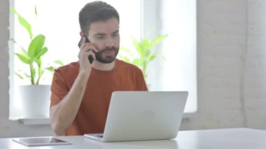 Angry Man Talking on Phone at Work