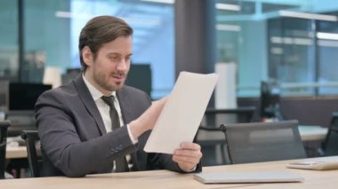 Young Businessman Celebrating Success while Reading Documents