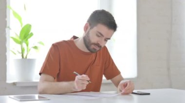 Creative Young Man Working on Documents in Office 