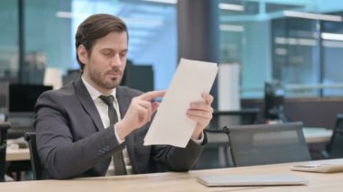 Young Businessman Reading Documents in Office, Paperwork
