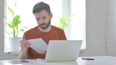 Paperwork by Creative Young Man while Using Laptop