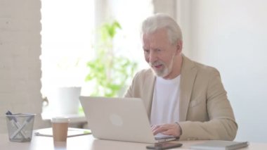 Senior Old Man Celebrating Success while using Laptop in Office