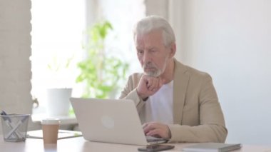 Senior Old Man Thinking while Working on Laptop in Office