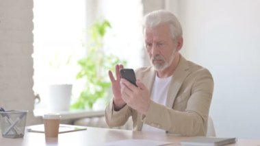 Senior Old Man Browsing Internet on Smartphone in Office 