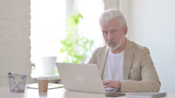 Starszy Staruszek Patrzący Kamerę Podczas Korzystania Laptopa Biurze — Wideo stockowe