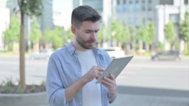 Upset Man Reacting to Loss on Tablet Outdoor