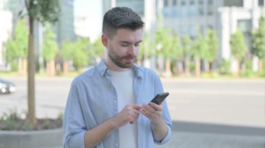 Man Celebrating Online Success on Smartphone Outdoor