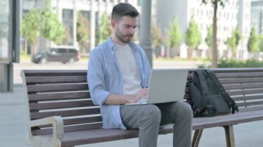 Man with Headache Using Laptop while Sitting on Bench