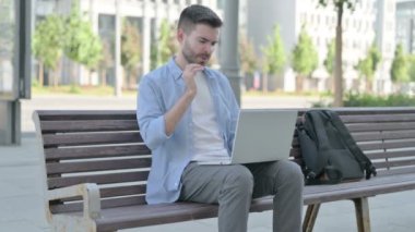 Man with Neck Pain Using Laptop while Sitting on Bench