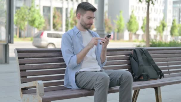 Άνθρωπος Περιήγηση Στο Internet Για Smartphone Ενώ Κάθεται Στο Bench — Αρχείο Βίντεο