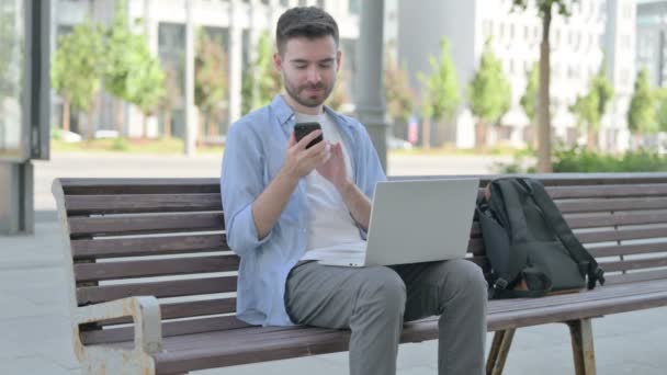 Man Talking Phone Using Laptop While Sitting Bench — Stockvideo