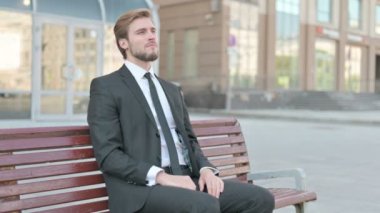 Middle Aged Businessman having Back Pain while Sitting on Bench Outdoor
