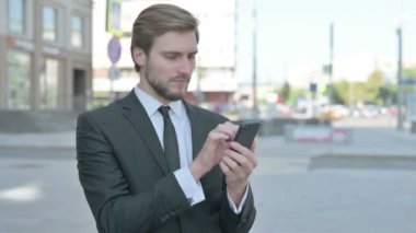 Middle Aged Businessman Browsing Internet on Smartphone Outdoor