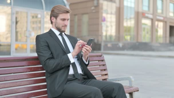 Middle Aged Businessman Celebrating Online Success Smartphone Outdoor Bench — Stockvideo