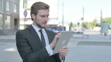 Upset Middle Aged Businessman Reacting to Loss on Tablet Outdoor