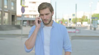 Kızgın Orta yaşlı adam dışarıda telefonla konuşuyor.