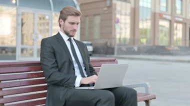 Middle Aged Businessman with Back Pain Using Laptop while Sitting Outdoor on Bench