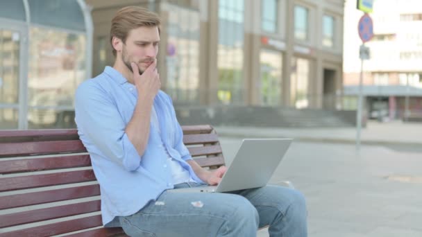 Denkender Mann Mittleren Alters Benutzt Laptop Während Draußen Auf Bank — Stockvideo