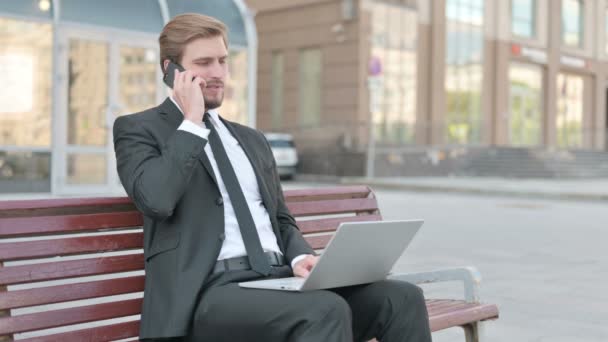 Middle Aged Businessman Talking Phone Using Laptop While Sitting Outdoor — Vídeos de Stock