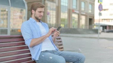 Smartphone 'da Çevrimiçi Başarıyı Kutlayan Orta Yaşlı Adam Bench' te Dışarıda Otururken