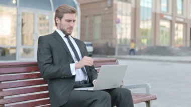 Coughing Middle Aged Businessman Using Laptop while Sitting Outdoor on Bench
