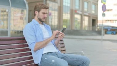 Orta yaşlı bir adam Bench 'te otururken Smartphone' da Kayıplara Tepki Veriyor