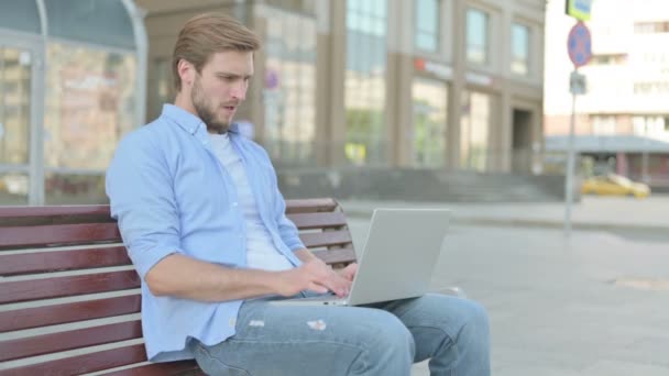 Hustender Mann Mittleren Alters Benutzt Laptop Während Draußen Auf Bank — Stockvideo
