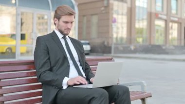 Middle Aged Businessman with Laptop Showing Thumbs Up Sign While Sitting Outdoor on Bench 