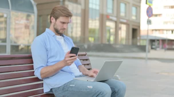 Mann Mittleren Alters Benutzt Smartphone Und Laptop Während Draußen Auf — Stockvideo