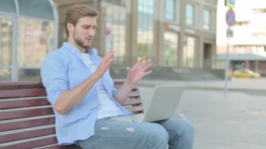 Orta yaşlı bir adam Bench 'te otururken görüntülü konuşma yapıyor.