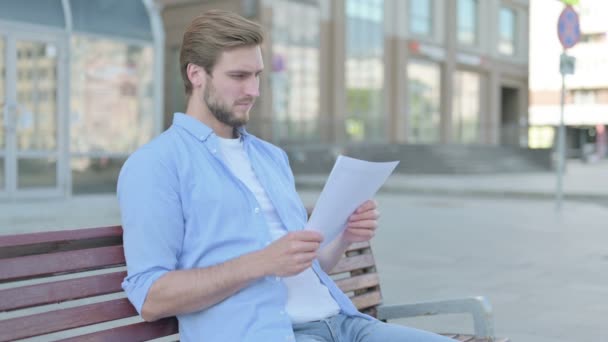 Mann Mittleren Alters Liest Dokumente Während Auf Bank Freien Sitzt — Stockvideo