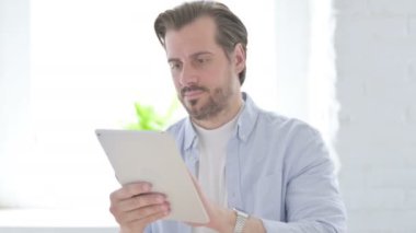 Mature Man Celebrating on Tablet in Office 